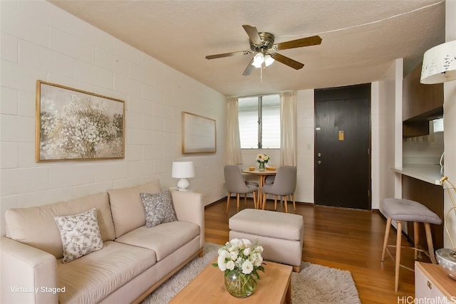 living room with a textured ceiling, hardwood / wood-style flooring, and ceiling fan