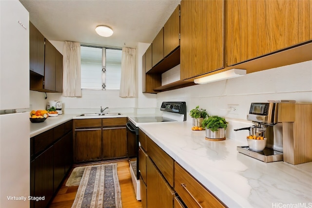 kitchen with light hardwood / wood-style floors, sink, backsplash, range with electric cooktop, and white refrigerator