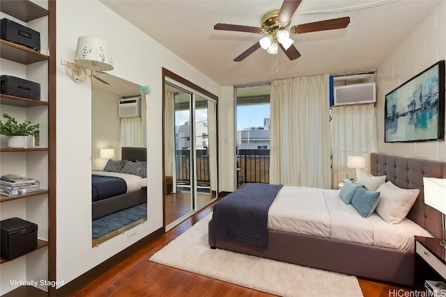 bedroom with ceiling fan, dark hardwood / wood-style floors, a textured ceiling, and a wall mounted air conditioner