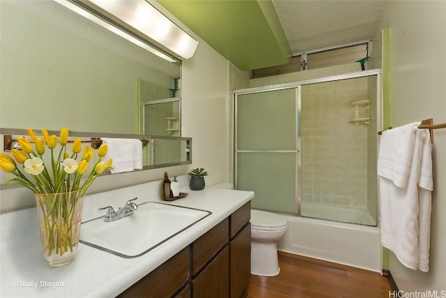 full bathroom featuring toilet, vanity, wood-type flooring, and enclosed tub / shower combo