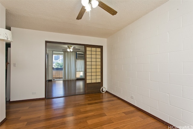 empty room with dark wood-type flooring, a textured ceiling, ceiling fan, and a wall mounted air conditioner