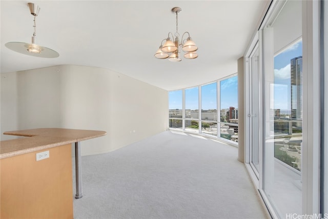 unfurnished living room featuring light colored carpet, an inviting chandelier, and floor to ceiling windows