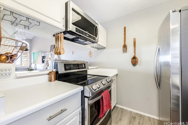 kitchen with light hardwood / wood-style floors, white cabinetry, and appliances with stainless steel finishes