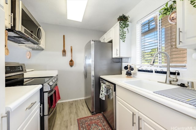 kitchen with sink, white cabinets, stainless steel appliances, and light wood-type flooring