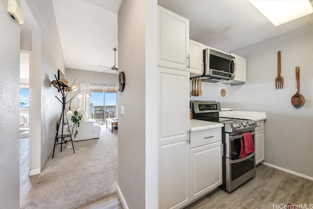 kitchen with white cabinets, light wood-type flooring, stainless steel appliances, and ceiling fan