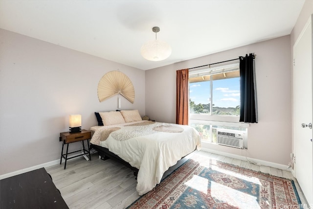 bedroom with an AC wall unit and light hardwood / wood-style floors