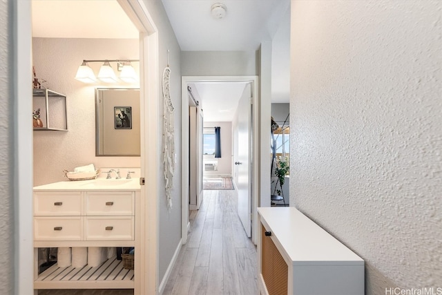 hall with light wood-type flooring and sink