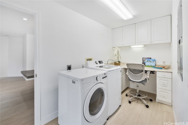 laundry room featuring washer and dryer, cabinets, and light wood-type flooring