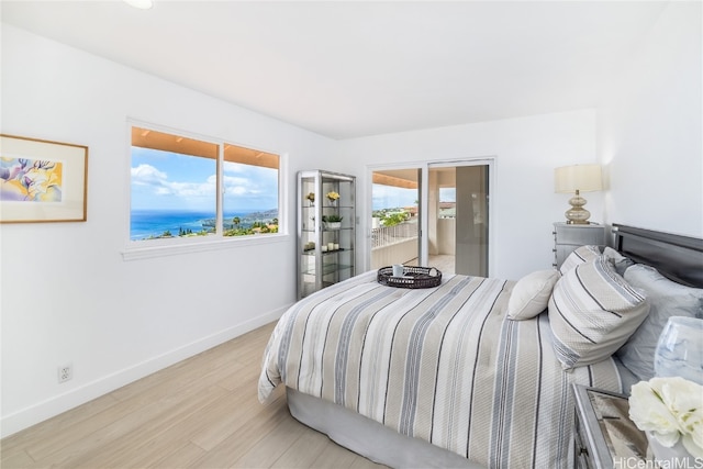 bedroom with light hardwood / wood-style flooring and a water view