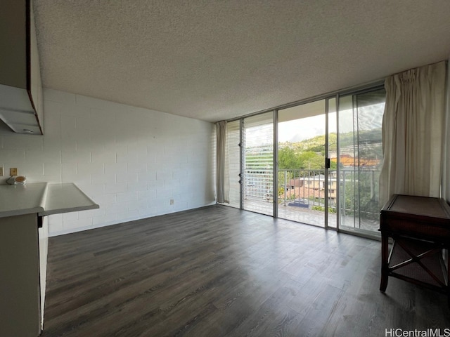 unfurnished living room featuring a textured ceiling, a wall of windows, and dark hardwood / wood-style floors