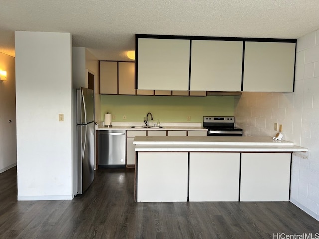 kitchen featuring dark hardwood / wood-style floors, kitchen peninsula, sink, appliances with stainless steel finishes, and a textured ceiling