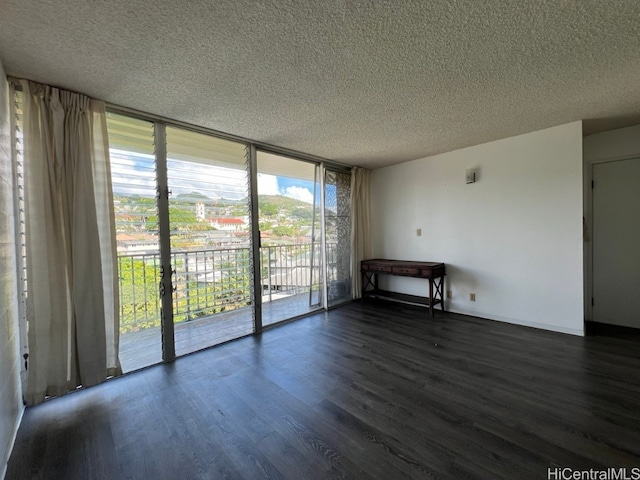 spare room with a textured ceiling, expansive windows, a wealth of natural light, and dark hardwood / wood-style floors