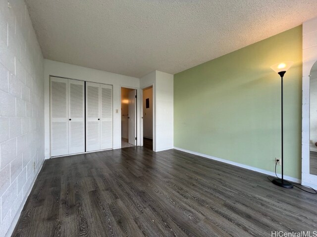 unfurnished bedroom featuring a closet, a textured ceiling, and dark wood-type flooring