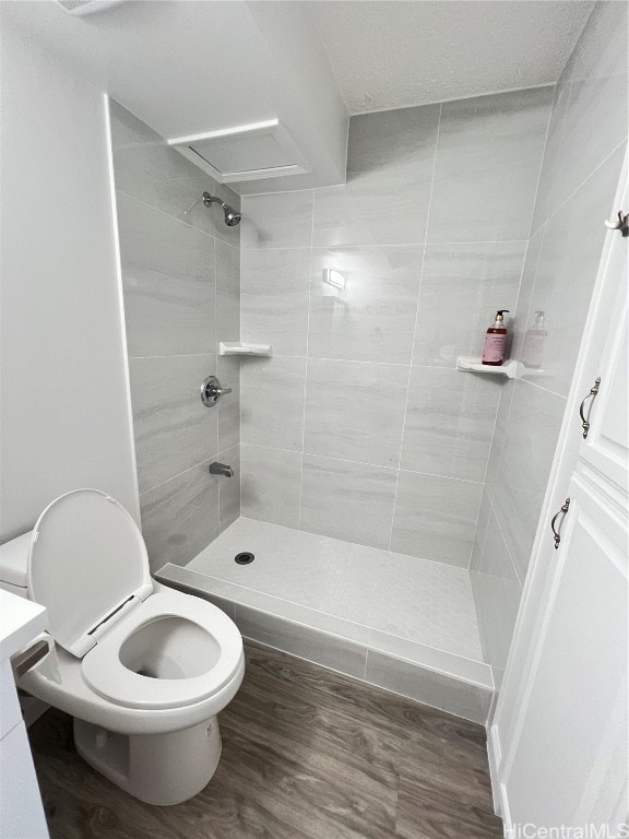 bathroom with vanity, toilet, wood-type flooring, and tiled shower