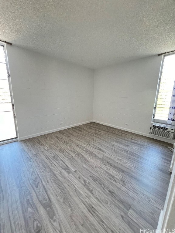 spare room with a textured ceiling, light hardwood / wood-style flooring, and cooling unit