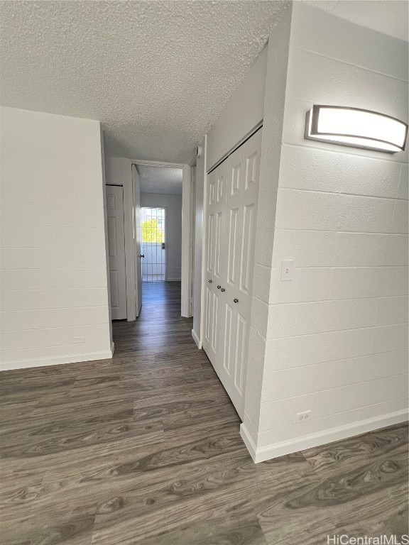 corridor featuring a textured ceiling and dark hardwood / wood-style floors