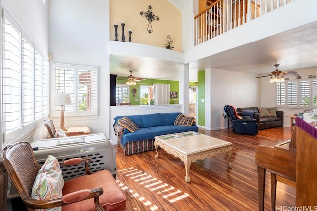 living room with wood-type flooring, a towering ceiling, and ceiling fan