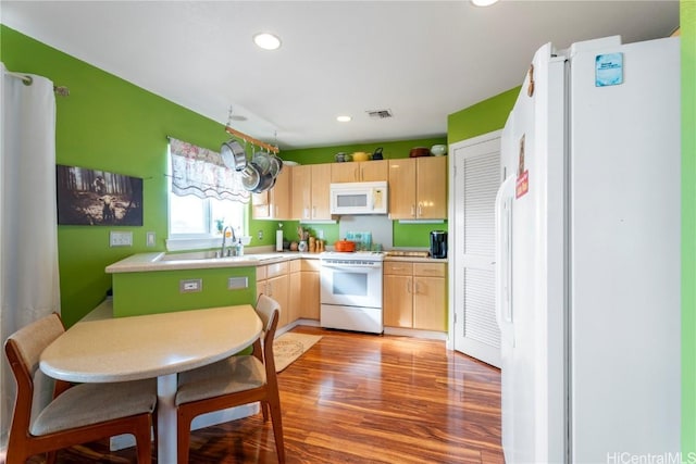 kitchen with sink, white appliances, wood-type flooring, and light brown cabinets