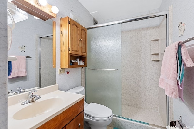 bathroom featuring vanity, toilet, and a shower with shower door