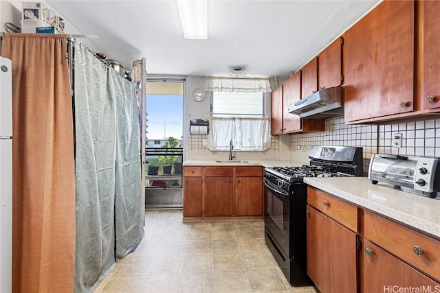 kitchen featuring light tile patterned floors, gas stove, tasteful backsplash, and sink