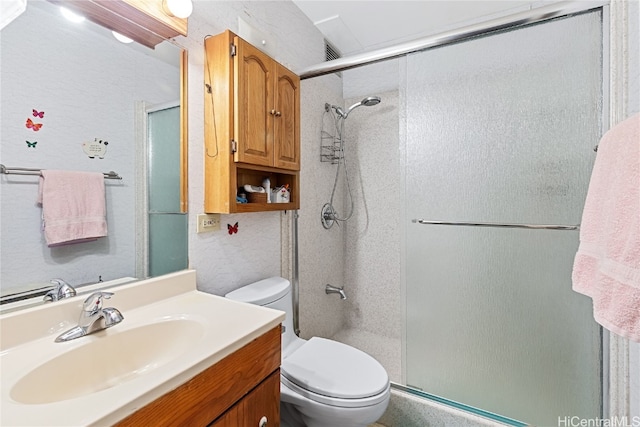 bathroom with a shower with door, vanity, and toilet