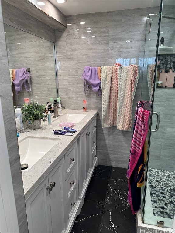 bathroom featuring a shower with door, vanity, and tile walls