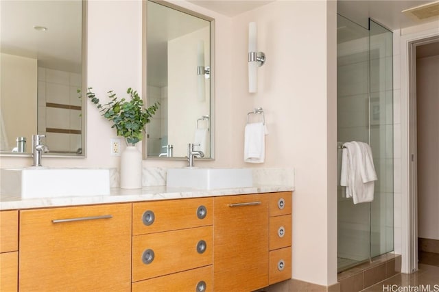 bathroom with double vanity, a stall shower, and a sink