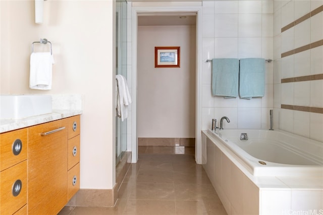 bathroom featuring tile patterned flooring, vanity, and tiled bath