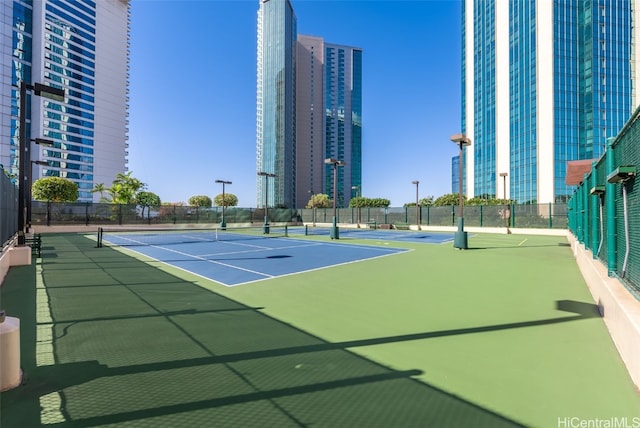 view of sport court featuring a view of city and fence