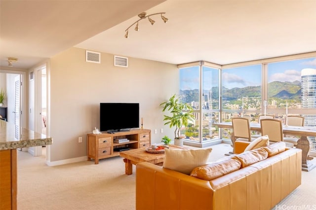 living room featuring baseboards, visible vents, a wall of windows, and light colored carpet