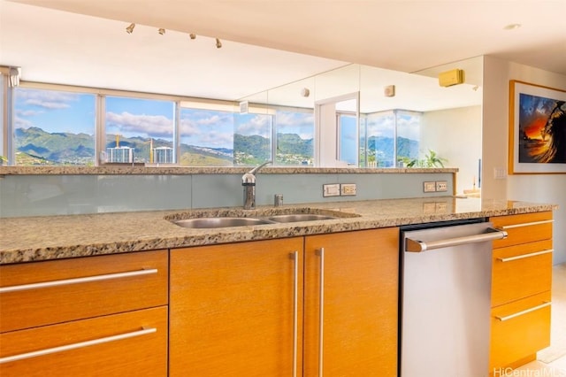 kitchen with light stone counters, a sink, dishwasher, and a mountain view