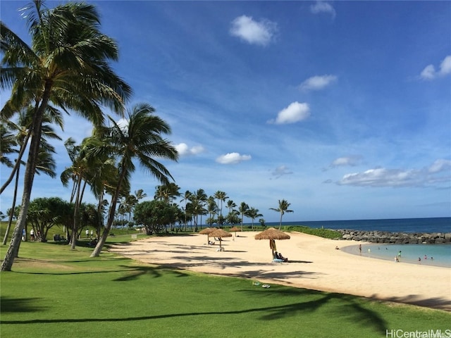 surrounding community with a yard, a water view, and a view of the beach