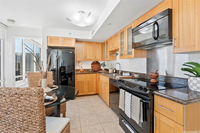 kitchen featuring light brown cabinets, black appliances, a sink, and glass insert cabinets