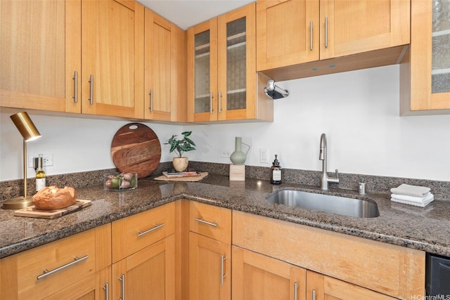 kitchen with glass insert cabinets, dishwasher, dark stone counters, and a sink