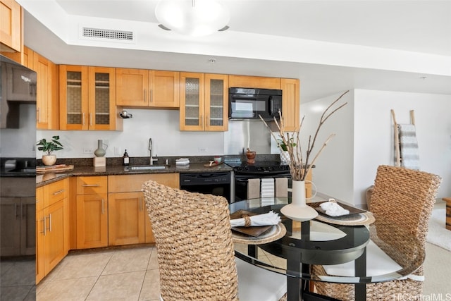 kitchen featuring light tile patterned floors, sink, dark stone countertops, and black appliances