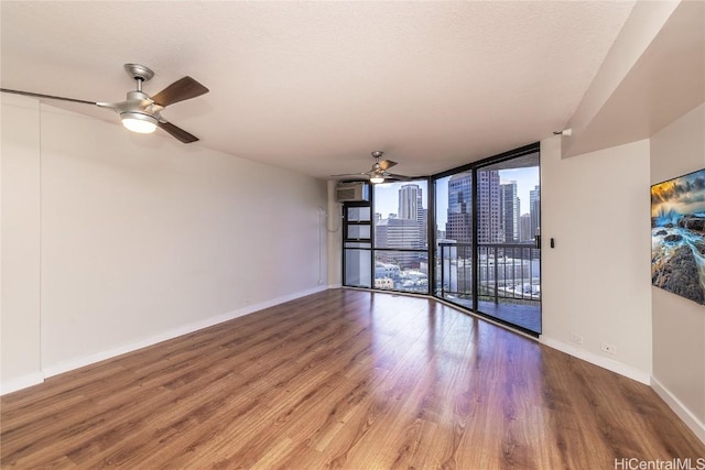 empty room featuring wood-type flooring, a textured ceiling, floor to ceiling windows, and ceiling fan