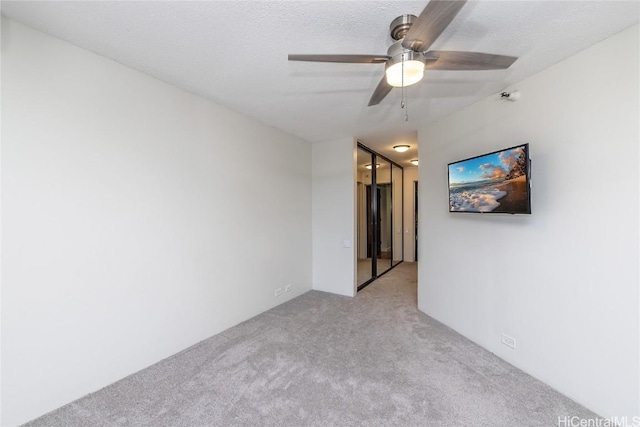 carpeted spare room with ceiling fan and a textured ceiling