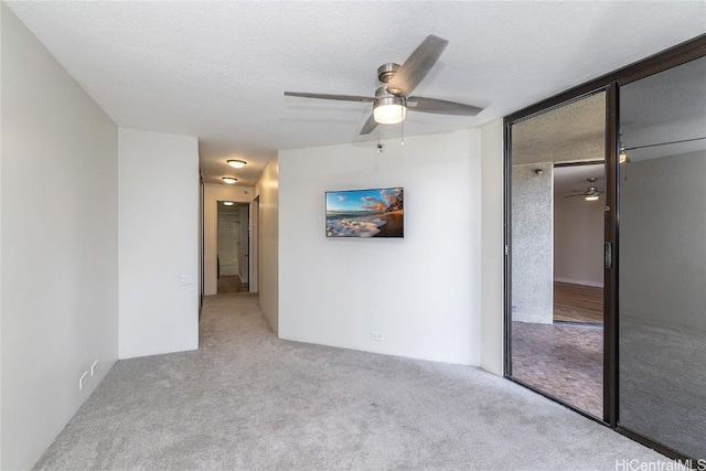 carpeted empty room featuring ceiling fan and a textured ceiling