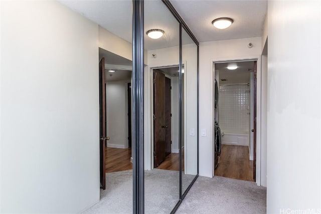 hallway with a textured ceiling and light hardwood / wood-style floors