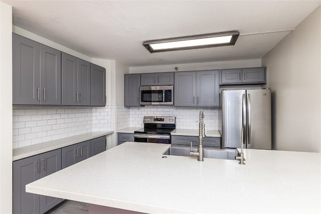 kitchen with gray cabinetry, sink, stainless steel appliances, tasteful backsplash, and a textured ceiling