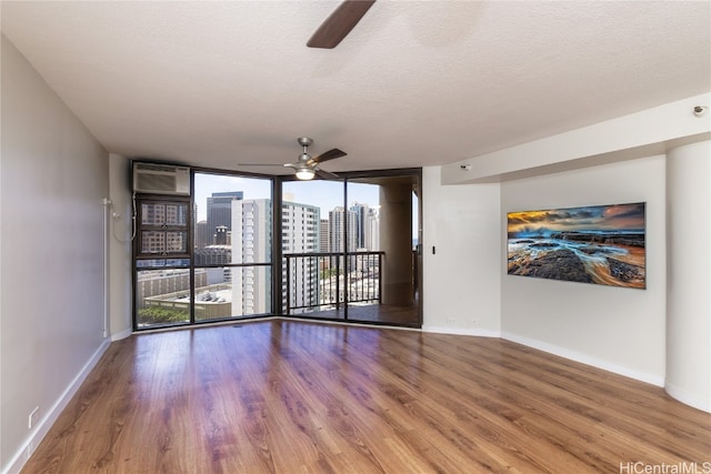 spare room with hardwood / wood-style flooring, ceiling fan, a wall of windows, and a textured ceiling