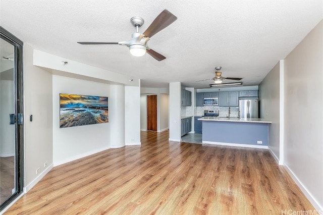 unfurnished living room with ceiling fan, hardwood / wood-style floors, and a textured ceiling