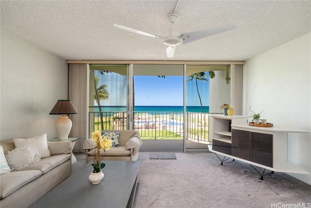 carpeted living room with a textured ceiling, a water view, and expansive windows