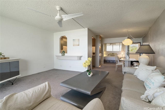 living room featuring carpet flooring, ceiling fan, and a textured ceiling