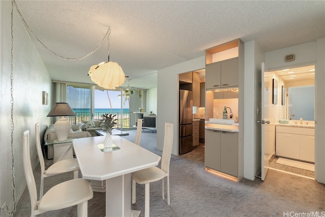 carpeted dining room with floor to ceiling windows, sink, a textured ceiling, and a water view