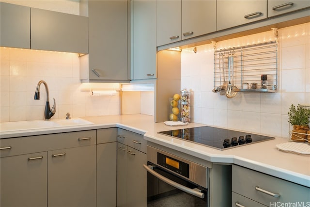 kitchen featuring sink, tasteful backsplash, oven, and black electric cooktop