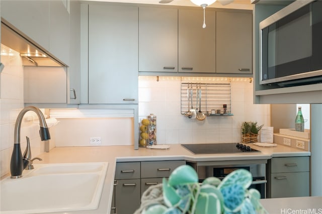 kitchen featuring tasteful backsplash, gray cabinets, sink, and black stovetop