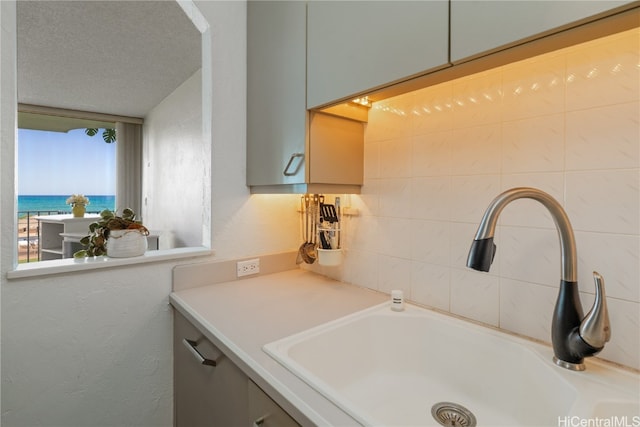 interior space featuring a textured ceiling, a water view, and sink