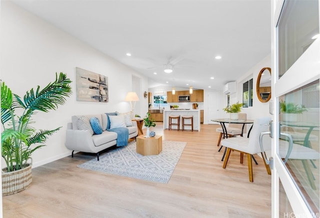 living room with a wall mounted air conditioner, vaulted ceiling, light hardwood / wood-style flooring, and ceiling fan