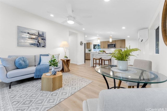 living room featuring a wall mounted air conditioner, vaulted ceiling, light hardwood / wood-style flooring, and ceiling fan